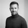 Minimalist monochrome studio headshot of a seasoned fintech CTO in a dark turtleneck.